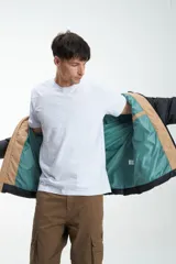 Campera puffer negra y beige con cierre frontal y cuello alto. Estampado con la marca "Unfrm" en el pecho.