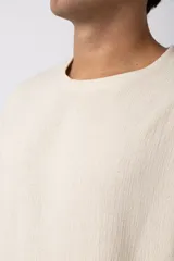 Remera de manga corta con cuello redondo, confeccionada en tejido de lino con textura entramada y corte holgado.