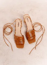Sandalia de cuero tostado con múltiples tiras finas en la parte delantera, punta cuadrada y taco medio de diseño acampanado. Cuenta con cordones largos para atar alrededor del tobillo.