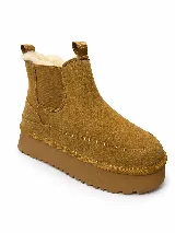 Pantubotas de gamuza color tostado, con plataforma gruesa dentada, elásticos laterales y forro interno de corderito sintético.