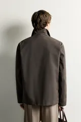 Sobrecamisa regular fit color marrón oscuro de algodón con estructura canvas, cuello solapa, manga larga, bolsillos frontales de parche y cierre de botonadura. Forro interior a cuadros en tonos marrón y beige.