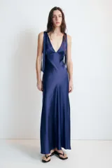 Vestido midi satinado color marrón, con escote en V y tirantes anchos ajustables con lazada en los hombros. Presenta cierre lateral con cremallera oculta.