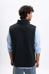 Chaleco de polar negro con cierre frontal completo, cuello alto y bolsillos laterales.