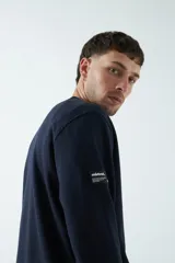 Buzo de felpa verde oliva con logo estampado en el frente, cuello redondo y puños. Confeccionado en 80% algodón y 20% poliéster.