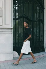 Top negro de manga corta con escote redondo y cierre frontal de botones forrados. Presenta un corte peplum con volado en la cintura.