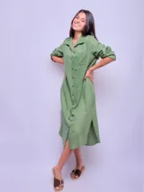 Vestido camisero largo color verde militar, confeccionado en lino, con cuello clásico, mangas largas con puños abotonados y cierre frontal con botones. Incluye un bolsillo de parche en el pecho.