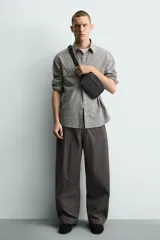 Riñonera negra con textura grabada, compartimento principal con cierre de cremallera y bolsillo frontal plano. Incluye asa ajustable con hebilla metálica de liberación rápida.