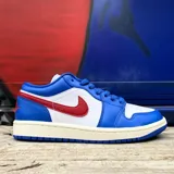 Championes Nike Air Jordan 1 Low con diseño de paneles en cuero blanco y azul, destacando el swoosh lateral en color rojo. Presenta el logo Jordan Wings bordado en el talón y suela de goma en color azul.