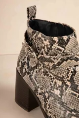 Botas de caña baja color negro, con taco cuadrado, punta fina y detalle de tira con textura de piel de reptil y hebilla metálica.