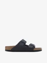 Sandalia de dos tiras ajustables con hebillas metálicas, color negro mate. Presenta la clásica plantilla anatómica de corcho y látex con forro de ante y suela de EVA.