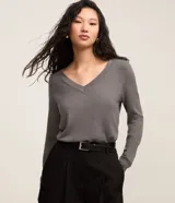 Suéter de punto color amarillo, con escote en V y mangas largas. Presenta un diseño básico y versátil, confeccionado en una mezcla de viscosa, poliamida y elastano.