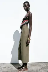 Pantalón de lino negro, de tiro alto, con bolsillos delanteros de vivo, pernera recta y cierre frontal con cremallera, botón interior y gancho metálico.