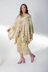 Vestido corto con estampado de hojas en tonos beige y amarillo, sin mangas y escote redondo. Incluye un poncho a juego con el mismo estampado.