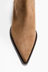 Botines de gamuza color marrón con punta fina y taco kitten. Presentan un diseño minimalista con cierre lateral y forro interior de satén.