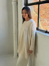 Sweater de punto color crudo, con cuello redondo, manga larga y diseño holgado con costura central vertical.