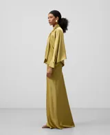 Falda larga verde oliva satinada con cinturilla elástica interior, cierre de cremallera lateral, corte al bies y bajo evasé.