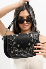 Bandolera de cuero negro con estructura rígida, tapa frontal decorada con tachas metálicas plateadas colocadas a mano y correa larga ajustable.