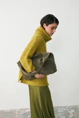 Cartera tipo tote de gran capacidad, confeccionada en cuero agamuzado color verde seco. Presenta un diseño minimalista con asa única ancha integrada para llevar al hombro.
