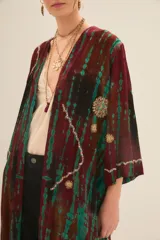 Kimono largo abierto, de corte recto y mangas largas, confeccionado en viscosa con teñido tie dye en tonos borgoña y turquesa. Presenta bordados con lentejuelas, mostacillas, canutillos e hilos de lurex en los bordes y en el frente.