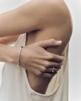 Brazalete rígido plateado de la marca PDPAOLA, modelo Aire, con diseño sutilmente ondulado e incrustaciones de circons en la parte superior.