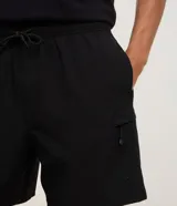 Bermuda Blue Steel de corte clásico, confeccionada en tejido ripstop de poliamida con elastano, en color verde militar. Cuenta con cintura elástica con cordón de ajuste interno, bolsillos laterales y un bolsillo con cierre en el lateral del muslo.