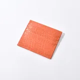 Tarjetero color naranja con textura símil cuero de cocodrilo y múltiples ranuras para tarjetas.
