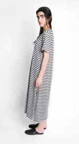 Vestido largo de corte recto, con cuello bote, mangas cortas y abertura lateral. Diseño a rayas horizontales en blanco y negro. Incluye lazo en la cintura.