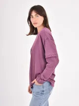 Remera de manga larga color bordó con efecto lavado, diseño de doble manga y estampado de estrellas en tono más claro en el frente.