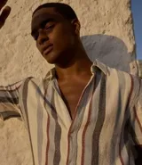 Camisa de hombre de manga corta con cuello tradicional y abotonado frontal total. Presenta un tejido texturizado con un patrón de rayas verticales en tonos crema, gris, azul claro y bordó.