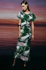 Vestido largo de corte ajustado, con estampado de hojas en tonos verdes, negros y blancos, y detalles en rosa. Tiene cuello redondo, mangas cortas y un frunce lateral en la falda.