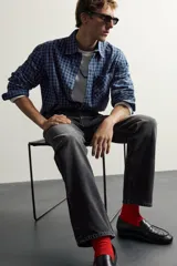 Jeans straight fit de corte recto y tiro medio, confeccionados en denim de algodón rígido con efecto lavado en color negro, de la colección especial Aaron Levine x Zara. Presentan diseño clásico de cinco bolsillos y cierre frontal con botonadura.