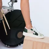 Zapatillas de cuero con plataforma baja, diseño multicolor que combina paneles en verde oscuro, dorado metalizado, blanco y detalles en rosa pastel. Presenta una estrella lateral con borde rosado, cordones blancos y pequeños remaches metálicos en la parte trasera.