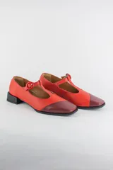 Zapatos de cuero tipo Mary Jane, color rojo con puntera diagonal en tono bordó, cierre de tira en T con hebilla y taco cuadrado bajo de 3 cm.