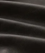 Campera estilo biker de poliuretano color marrón oscuro con efecto lavado, corte oversized, cuello con solapa, cierre frontal asimétrico y bolsillos con cierre.