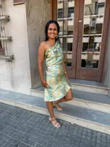 Conjunto de dos piezas compuesto por un top de un solo hombro con volados y una falda corta con ruedo asimétrico, confeccionado en tela satinada con estampado floral en tonos verde y dorado.