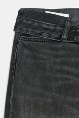 Jeans de mezclilla de tiro medio, corte wide leg y diseño relaxed. Presenta detalles rotos y desgastados en las piernas, y una cinturilla doblada superpuesta con trabillas y cierre frontal con cremallera y botón metálico.