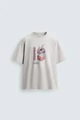 Camiseta relaxed fit color beige con cuello redondo y manga corta. Presenta un estampado frontal de un cartón de leche de fresa con una pajita, texto en japonés y la frase "SWEET MOMENTS".