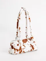 Cartera tipo baguette color marrón, de formato rectangular alargado y diseño rígido, con doble asa de hombro y argollas metálicas decorativas. Confeccionada en cuero.