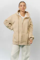 Campera deportiva con capucha de corte oversize, confeccionada en tejido suave con interior forrado en piel sintética. Presenta cierre frontal completo, bolsillos laterales y capucha amplia con cordones largos ajustables.