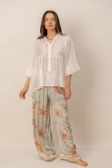 Pantalón fluido de tiro alto en color crudo con estampado floral en tonos naranjas y detalles de franjas laterales en azul marino.
