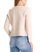 Chaqueta de punto color beige, con cuello redondo, cierre frontal mediante botones metálicos y bolsillos aplicados en la parte delantera.