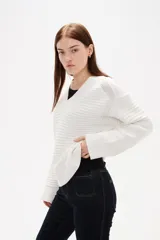 Sweater de punto color blanco, con cuello en V, manga larga y diseño holgado.