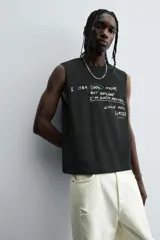Camiseta sin mangas (tank top) negra, corte boxy fit, con cuello redondo y sisa con acabado irregular. Presenta un estampado frontal con texto manuscrito en verde y blanco que dice: "I look cool online, but offline I'm even better... Chase real likes!".