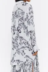 Camisa larga de corte recto, con cuello camisero, manga larga, puños con botones y cierre frontal con botonadura. Estampado con dibujos de animales y acróbatas en tinta negra.