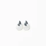 Caravanas de diseño minimalista con forma de gota, compuestas por una pieza superior metálica plateada y una pieza inferior de resina blanca con efecto nacarado.