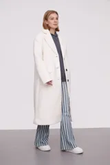 Tapado largo color marfil de poliéster con solapas, cierre con botones y corte holgado.