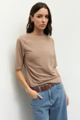 Remera negra de cuello redondo y manga tres cuartos, confeccionada en tela con textura sutil. Presenta fruncidos laterales que aportan caída y movimiento a la prenda.