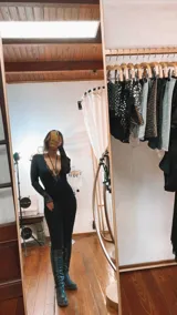 Body de lycra y encaje color negro, con mangas largas de tul transparente y detalle de encaje en los puños. Presenta un escote profundo con detalle de encaje y un collarín integrado que se conecta al centro del pecho.