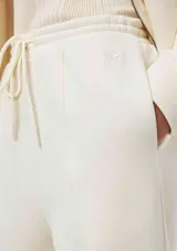 Pantalón de corte recto y holgado, color blanco, con cintura elástica y cordón ajustable. Presenta costuras verticales frontales que estilizan la silueta.