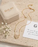 Collar de acero con baño de oro, compuesto por una cadena fina y un dije en forma de corazón pavé con incrustaciones de circonias.